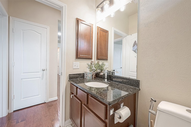 bathroom with hardwood / wood-style floors, toilet, and vanity