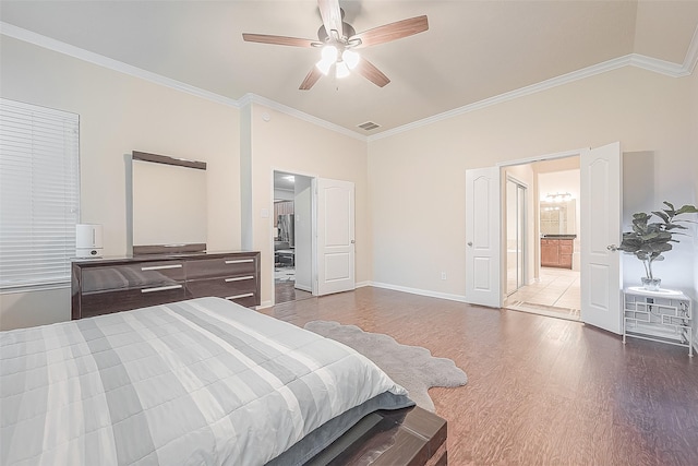 bedroom featuring crown molding, ensuite bath, wood-type flooring, and ceiling fan