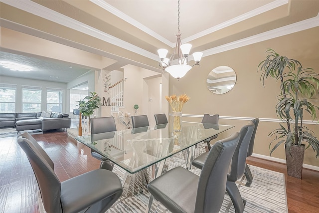 dining space featuring a tray ceiling, dark wood-type flooring, a notable chandelier, and crown molding