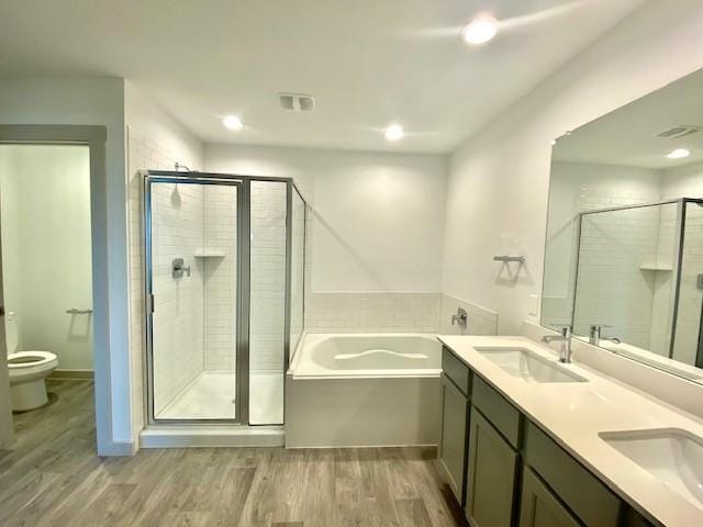 full bathroom with toilet, hardwood / wood-style flooring, independent shower and bath, and vanity