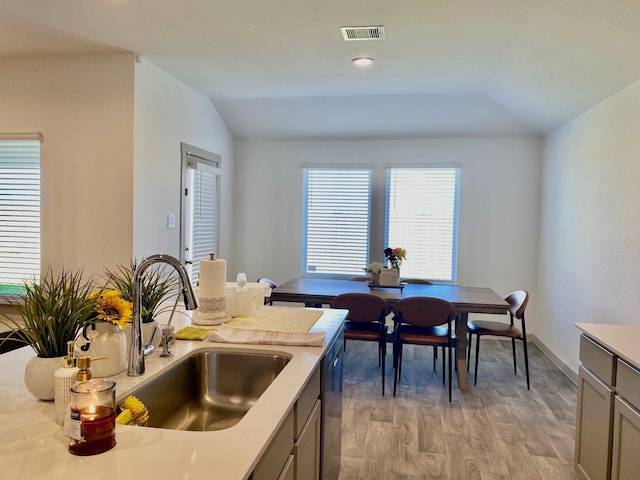 kitchen with sink, vaulted ceiling, gray cabinetry, and light hardwood / wood-style floors