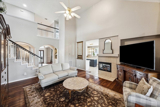 living room featuring lofted ceiling, ceiling fan, dark wood-type flooring, and a tiled fireplace