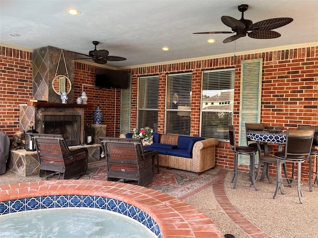 view of patio / terrace with ceiling fan and an outdoor living space with a fireplace