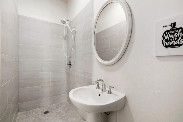 bathroom featuring tiled shower and sink