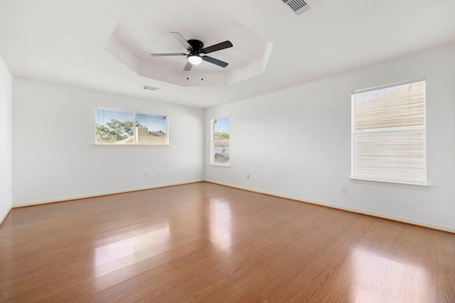 spare room with ceiling fan, wood-type flooring, and a raised ceiling