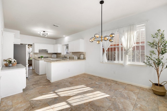 kitchen featuring a wealth of natural light, white cabinetry, decorative light fixtures, kitchen peninsula, and stainless steel refrigerator