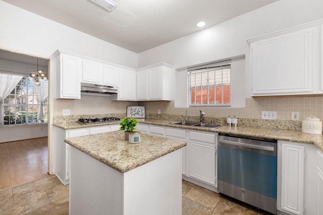 kitchen with stainless steel appliances, a center island, sink, white cabinets, and decorative backsplash