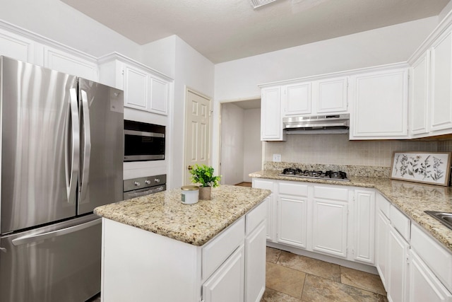 kitchen featuring stainless steel appliances, light stone counters, backsplash, a kitchen island, and white cabinetry