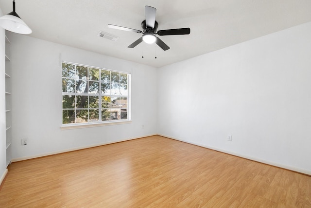 spare room with built in shelves, ceiling fan, and light hardwood / wood-style flooring