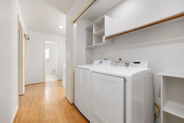 clothes washing area with independent washer and dryer and light wood-type flooring