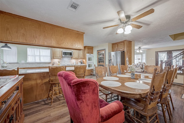 dining area with a textured ceiling, light wood-style flooring, and visible vents