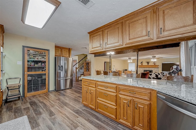 kitchen featuring dark wood-style floors, visible vents, appliances with stainless steel finishes, open floor plan, and light stone countertops