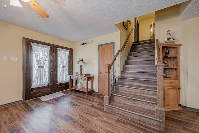 entrance foyer with french doors, a textured ceiling, wood finished floors, baseboards, and stairs