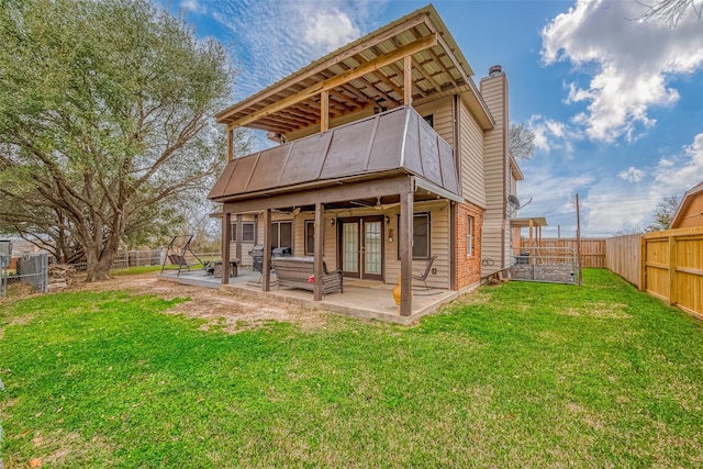 back of property with a fenced backyard, a chimney, a lawn, and a patio