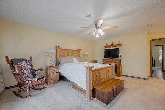 bedroom with a textured ceiling, ceiling fan, visible vents, and light colored carpet