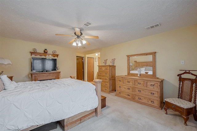 bedroom with light carpet, a textured ceiling, visible vents, and a ceiling fan