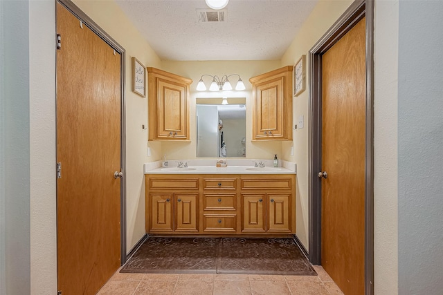 full bath with a textured ceiling, double vanity, a sink, and visible vents