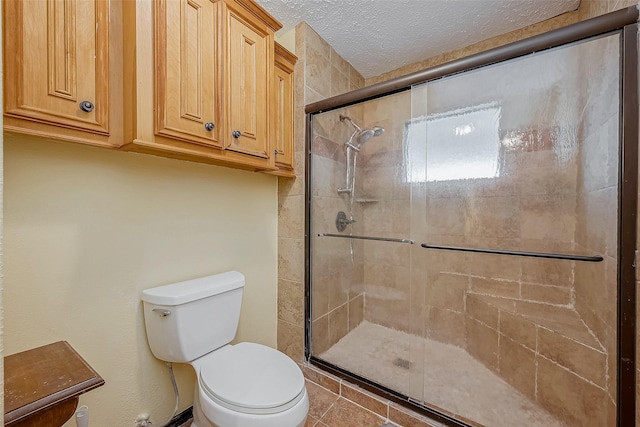 bathroom featuring a shower stall, toilet, and a textured ceiling