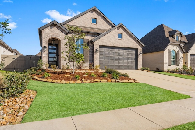 french provincial home featuring a garage, brick siding, concrete driveway, fence, and a front yard