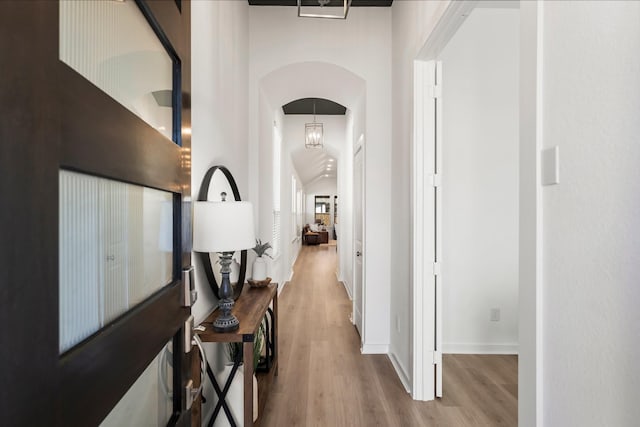 hallway featuring baseboards, arched walkways, and wood finished floors