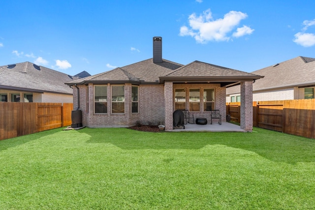 back of property with brick siding, a lawn, a patio area, and a fenced backyard