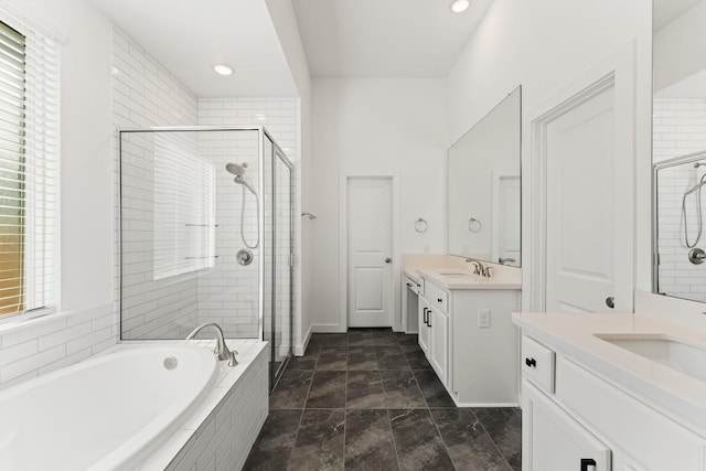 full bath featuring two vanities, a sink, a shower stall, and a garden tub