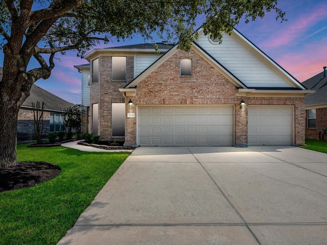 traditional-style home featuring a yard, driveway, brick siding, and an attached garage