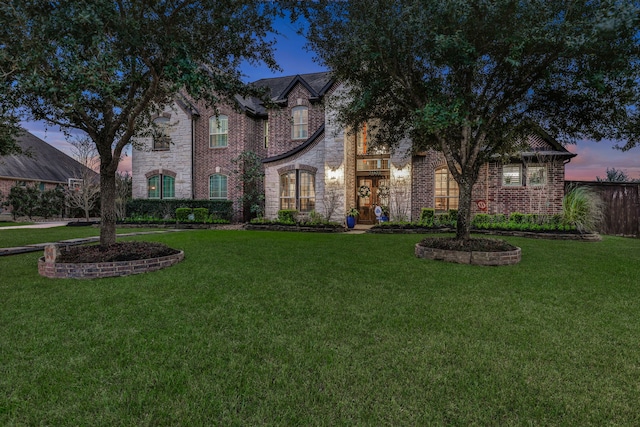 view of front of home featuring brick siding, a lawn, and stone siding