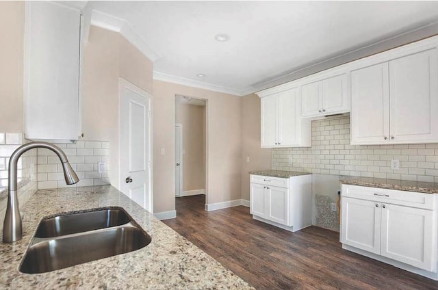 kitchen featuring light stone counters, dark wood-style flooring, white cabinets, and a sink