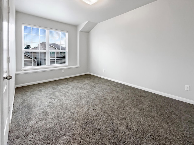 empty room with baseboards and dark colored carpet