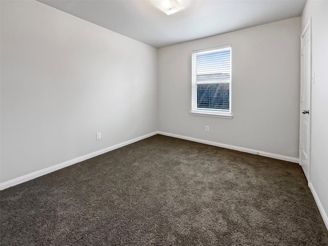 spare room with dark colored carpet and baseboards