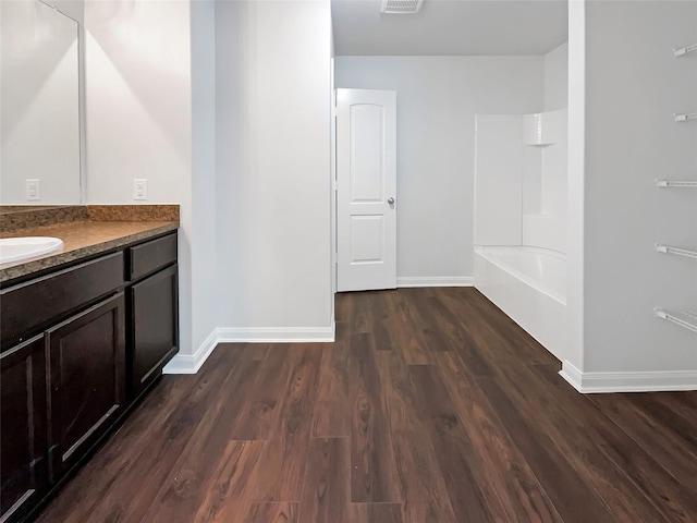 bathroom featuring visible vents, baseboards, bathing tub / shower combination, wood finished floors, and vanity