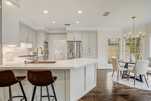 kitchen featuring appliances with stainless steel finishes, hanging light fixtures, white cabinets, crown molding, and dark hardwood / wood-style floors