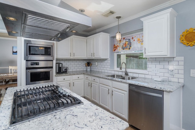 kitchen with appliances with stainless steel finishes, wall chimney range hood, decorative light fixtures, sink, and white cabinetry