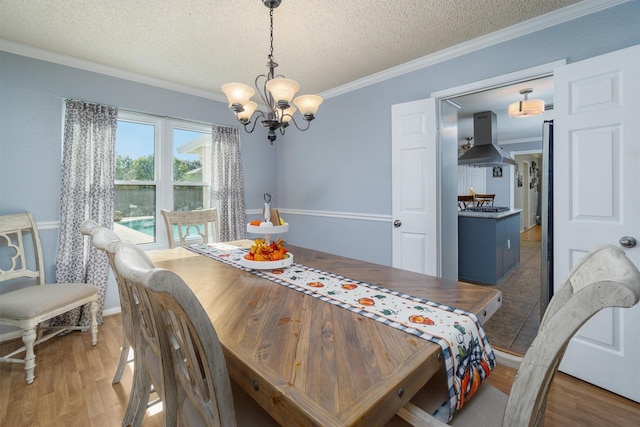 dining room with a textured ceiling, ornamental molding, and wood-type flooring