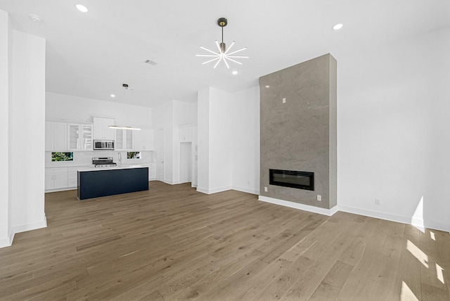 unfurnished living room featuring a notable chandelier, a large fireplace, and hardwood / wood-style floors