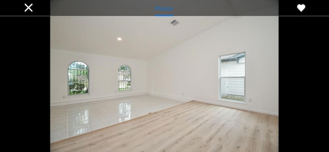 empty room with vaulted ceiling and light tile patterned floors