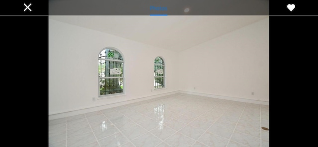 empty room with light tile patterned flooring and vaulted ceiling