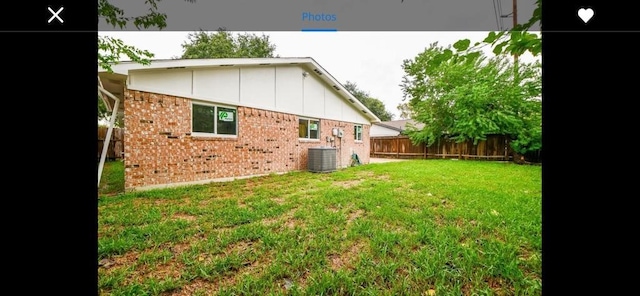 rear view of house with central AC unit and a yard