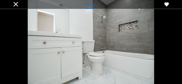 full bathroom with toilet, vanity, and tiled shower / bath combo