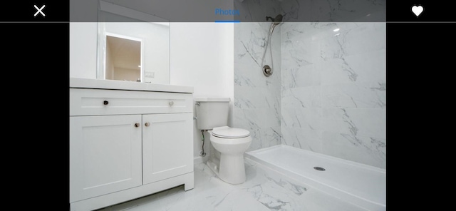 bathroom with vanity, tiled shower, and toilet