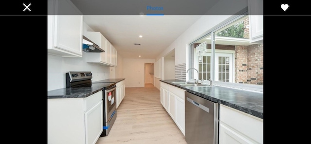 kitchen with appliances with stainless steel finishes, light hardwood / wood-style floors, backsplash, sink, and white cabinetry