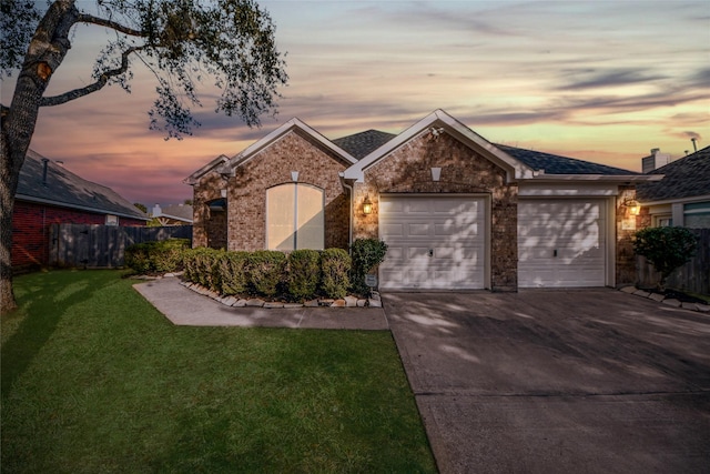 ranch-style home with a garage, concrete driveway, fence, a front yard, and brick siding