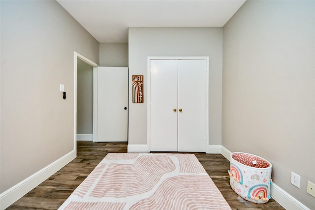 bedroom with a closet, baseboards, and dark wood-type flooring