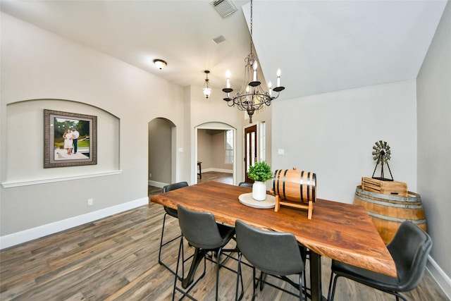 dining space featuring baseboards, visible vents, arched walkways, wood finished floors, and a chandelier