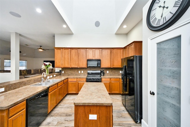 kitchen with light wood finished floors, decorative backsplash, light countertops, black appliances, and a sink