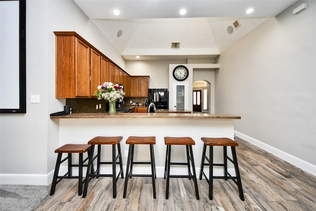 kitchen featuring freestanding refrigerator, backsplash, baseboards, and light wood finished floors