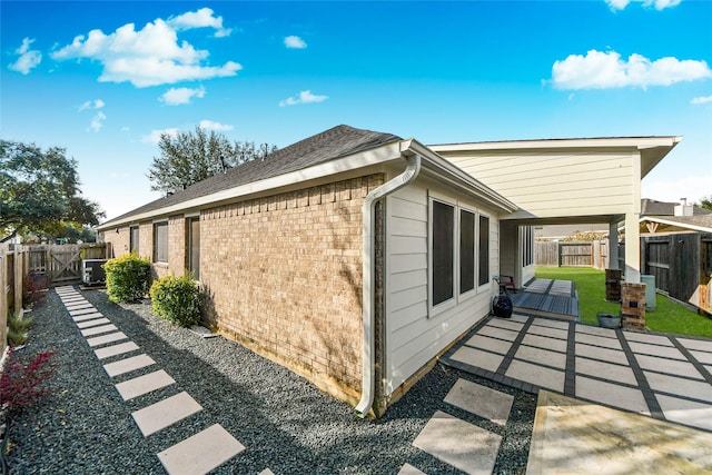 view of side of home featuring brick siding, a patio, and a fenced backyard