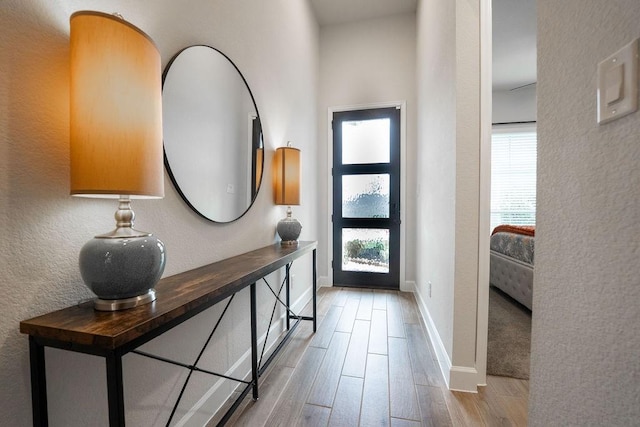 entrance foyer featuring baseboards, wood finished floors, and a textured wall