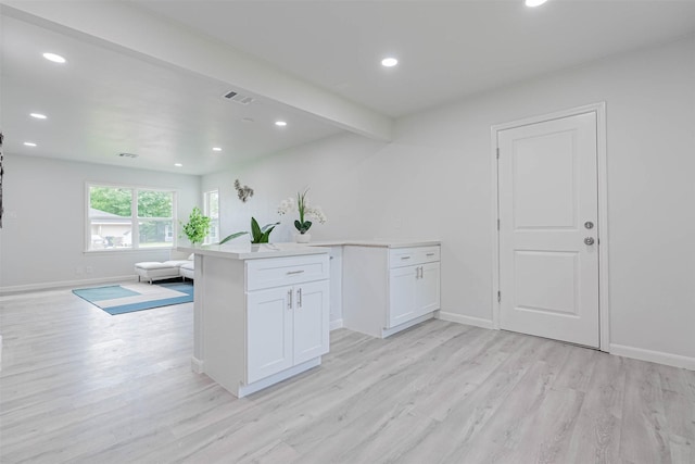 kitchen with beam ceiling, light hardwood / wood-style floors, and white cabinetry